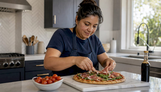 Woman placing prosciutto on freshly baked pizza