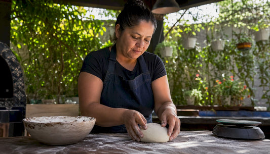 Home cook preparing pizza dough ball at kitchen table