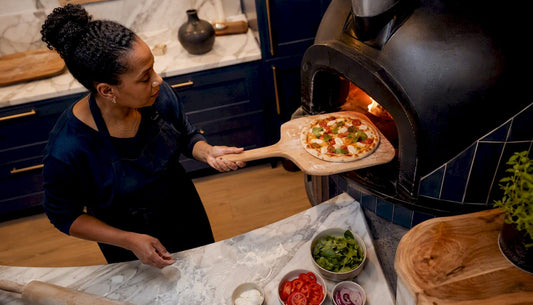 Home cook using wooden pizza peel by oven