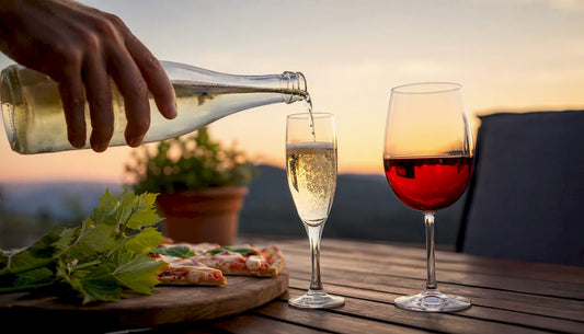 Pouring sparkling wine next to light red wine glass