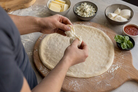 Hand tearing mozzarella over pizza dough