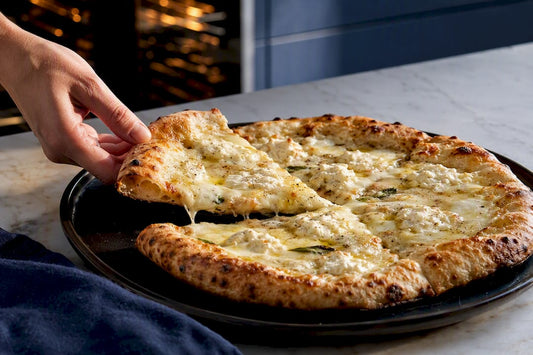 Ricotta dollops on a crisp white pizza
