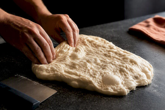 Hands rescuing slack overproofed pizza dough
