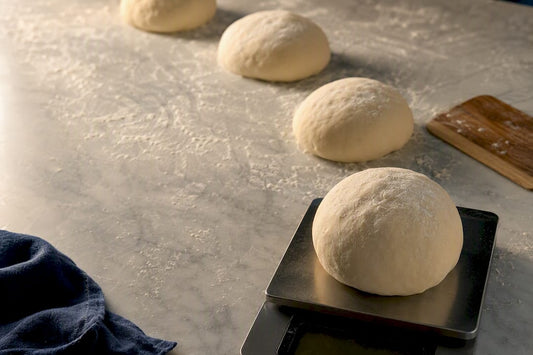 Pizza dough portions being weighed and shaped