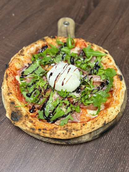 Neapolitan pizza topped with burrata, prosciutto, rocket and balsamic glaze, with a golden, charred crust on a wooden board.








Convert to PDF