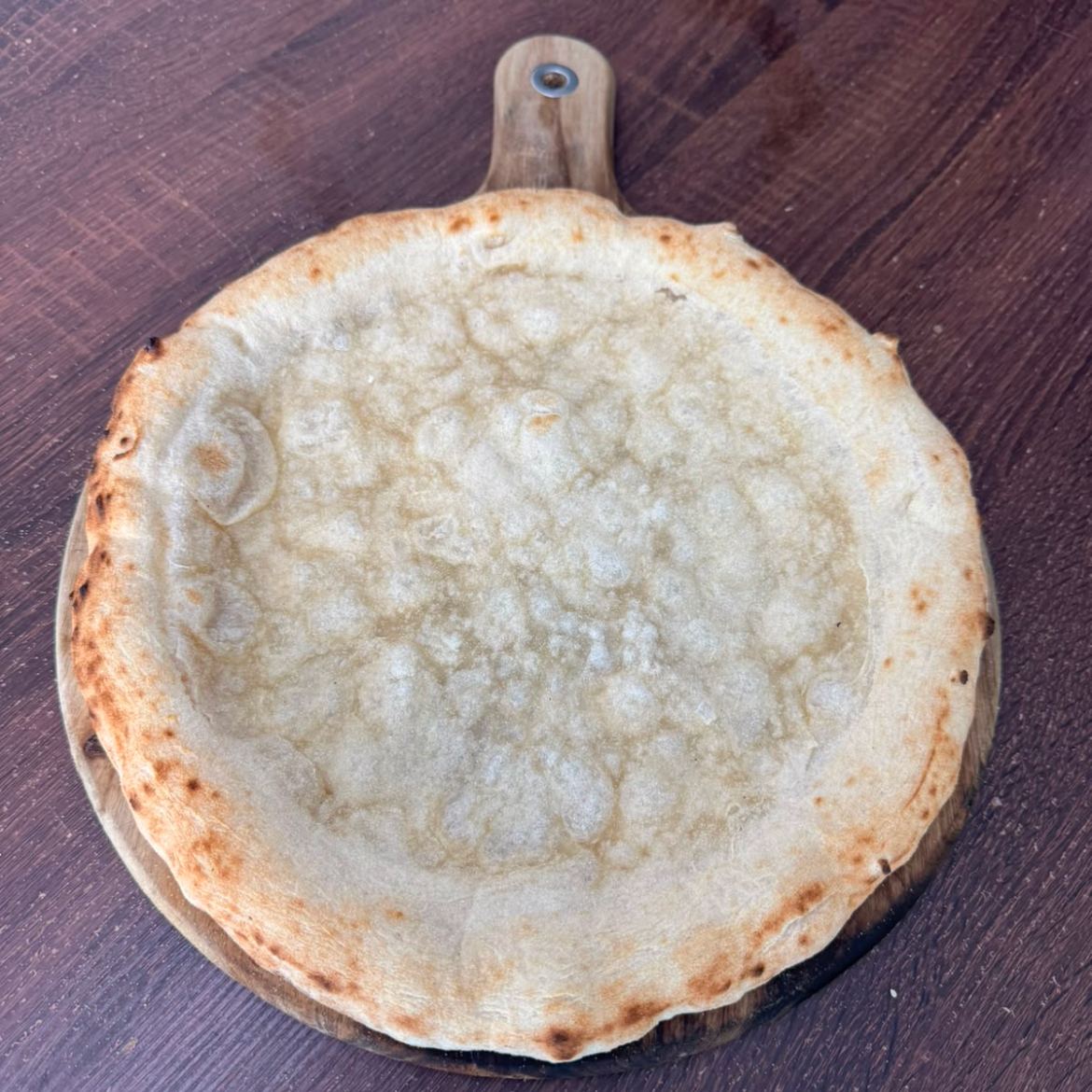 Dough Dorks pre-cooked Neapolitan pizza base on wooden board